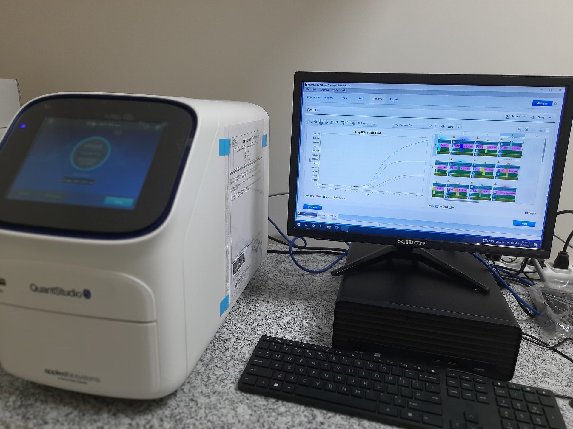 Equipamento de PCR em tempo real ao lado de monitor exibindo curvas de amplificação